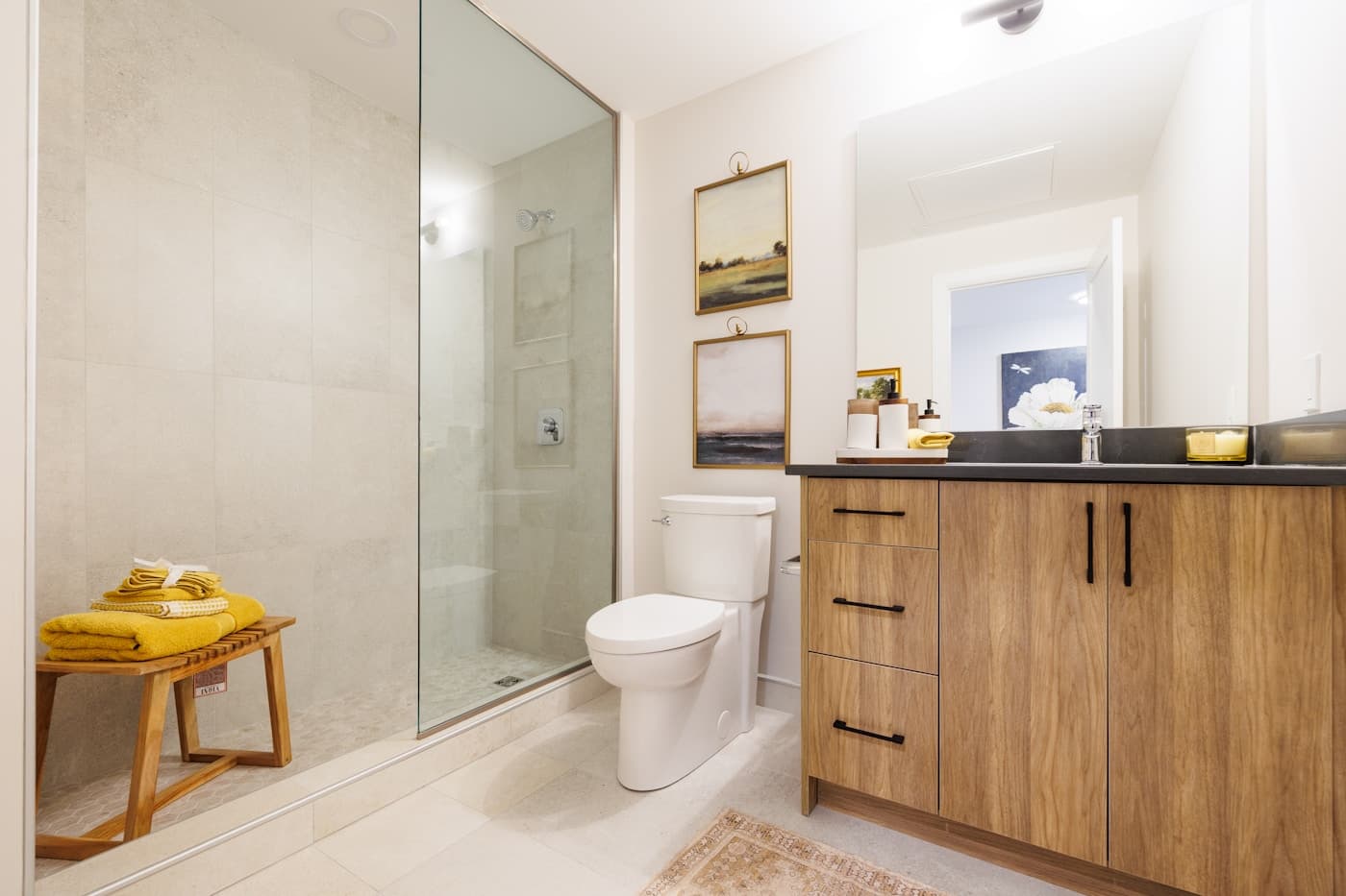 Modern bathroom vanity and glass shower in a bright, polished interior.